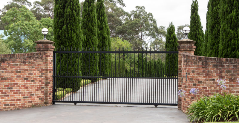 Black metal driveway entrance gates in brick fence