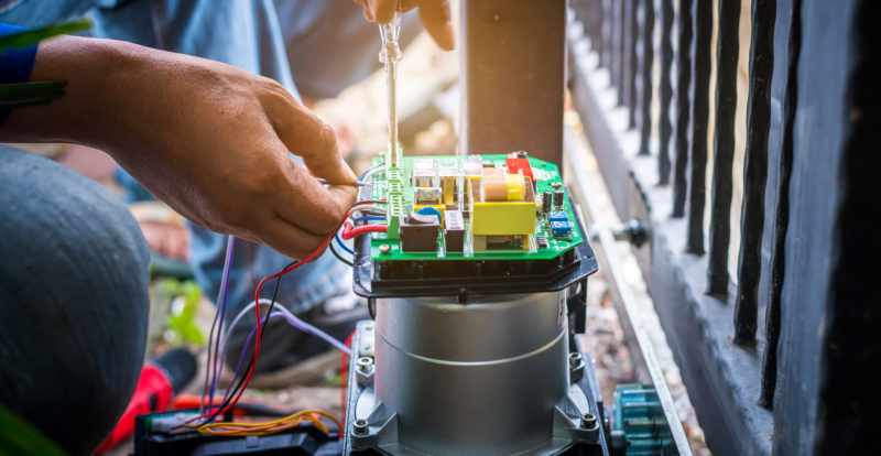 A Technician assembling motor system and testing motor automatic gate by screwdriver home security system.
